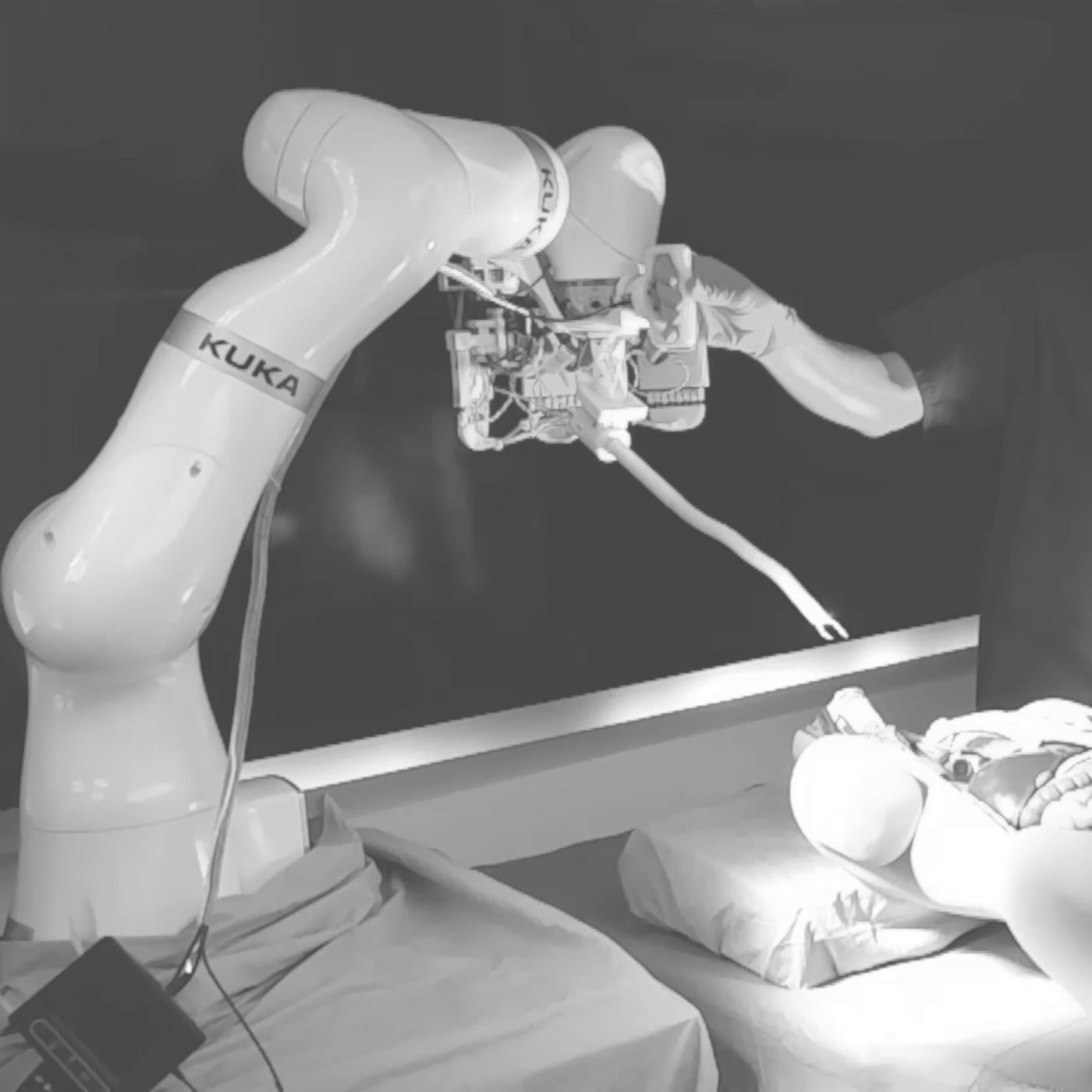 A robot arm holding a surgical instrument over a training torso